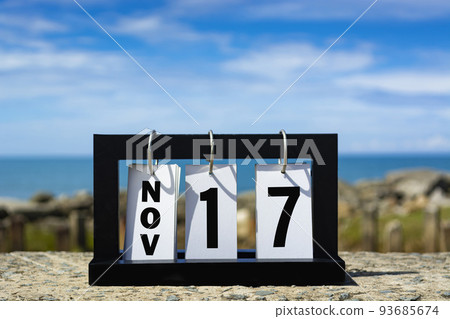 Nov 17 calendar date text on wooden frame with blurred background of ocean. Nov 17 calendar date text on wooden frame with blurred background of ocean. 93685674