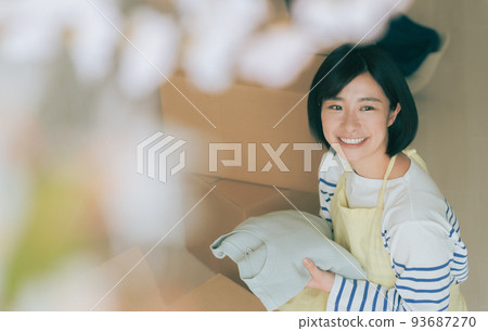 A woman putting clothes into a cardboard box 93687270