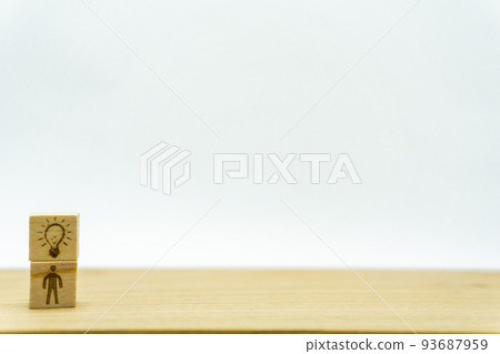 A man who seems to have an idea on a wooden cube with a person holding a light bulb A man who seems to have an idea on a wooden cube with a person holding a light bulb 93687959