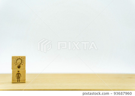 A woman who seems to have an idea on a wooden cube with a person holding a light bulb A woman who seems to have an idea on a wooden cube with a person holding a light bulb 93687960
