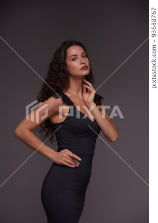Young fashion model in elegant black bandage dress standing in front of camera Young fashion model in elegant black bandage dress standing in front of camera 93688767