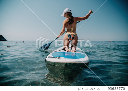 SUP Stand up paddle board. Young woman sailing on beautiful calm sea with crystal clear water. The concept of an summer holidays vacation travel, relax, active and healthy life in harmony with nature. SUP Stand up paddle board. Young woman sailing on beautiful calm sea with crystal clear water. The concept of an summer holidays vacation travel, relax, active and healthy life in harmony with nature. 93688770