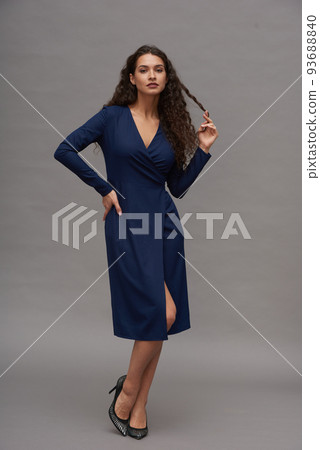 Young flirty woman in blue dress and high heeled shoes posing for camera Young flirty woman in blue dress and high heeled shoes posing for camera 93688840