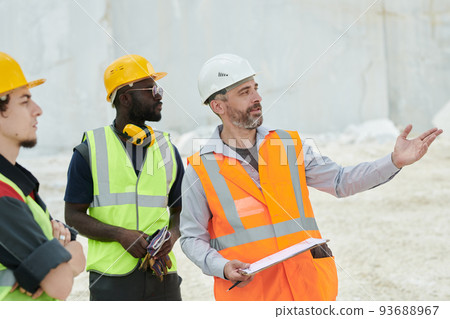 Middle aged foreman in workwear pointing at new industrial equipment Middle aged foreman in workwear pointing at new industrial equipment 93688967