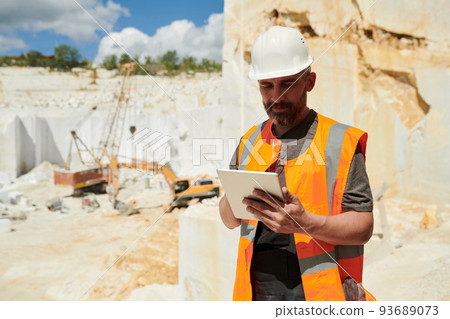 Middle aged foreman with tablet looking through online instruction at workplace 93689073