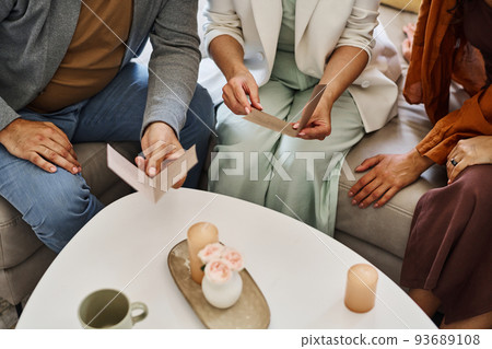 Mature couple in smart casualwear sitting on couch and reading invitation cards 93689108