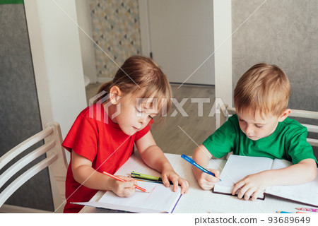Children sit at the table and write in notebooks. Homeschooling concept, learning online 93689649