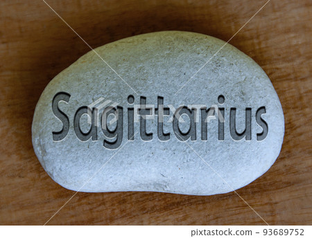 Sagittarius zodiac sign text engraved on a stock with wooden background. Zodiac sign concept. Sagittarius zodiac sign text engraved on a stock with wooden background. Zodiac sign concept. 93689752