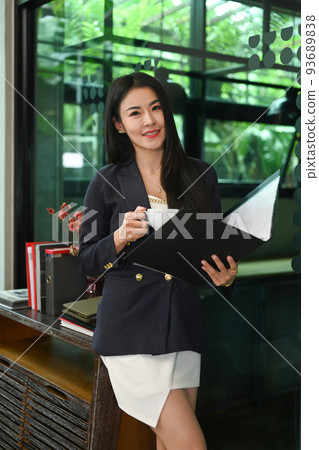 Gorgeous millennial businesswoman standing in corporate office and reading financial reports 93689838