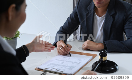 Shot of lawyer or attorney explaining terms, condition on legal document to client before signing on contract at law firm Shot of lawyer or attorney explaining terms, condition on legal document to client before signing on contract at law firm 93689899