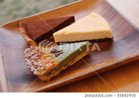 Matcha tart, cheesecake, chocolate tart and baked goods served on an acacia plate 93692450