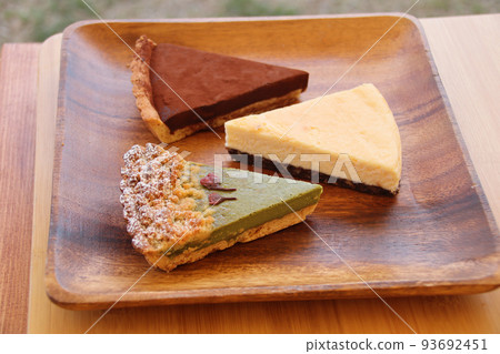 Matcha tart, cheesecake, chocolate tart and baked goods served on an acacia plate Matcha tart, cheesecake, chocolate tart and baked goods served on an acacia plate 93692451