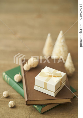 A gift box placed on a book and a tabletop Christmas tree 93692941