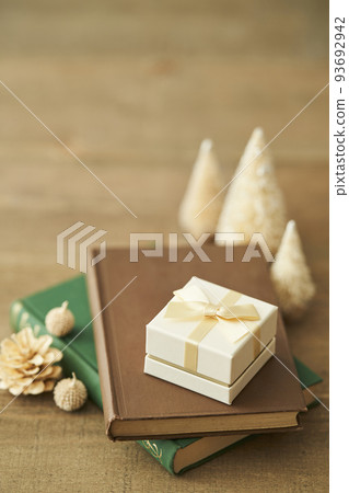 A gift box placed on a book and a tabletop Christmas tree 93692942
