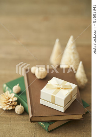 A gift box placed on a book and a tabletop Christmas tree 93692943