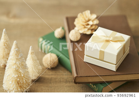 A gift box placed on a book and a tabletop Christmas tree 93692961