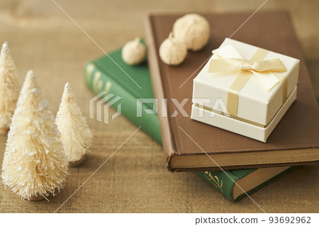 A gift box placed on a book and a tabletop Christmas tree 93692962