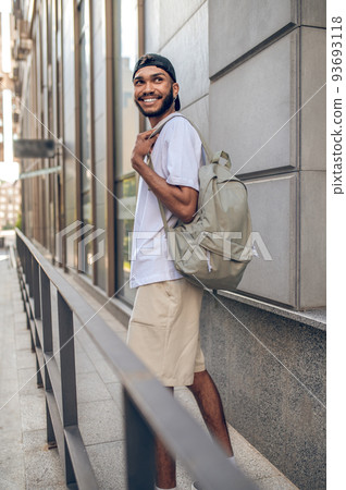 A handsome smiling man with a backpack in the city street 93693118
