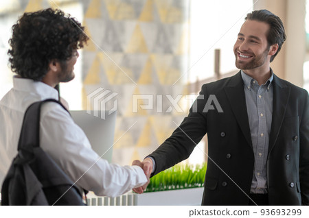Young manager welcoming new employee and looking positive Young manager welcoming new employee and looking positive 93693299