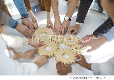 Close up of wooden gears that business people connect together during teambuilding session. 93693429