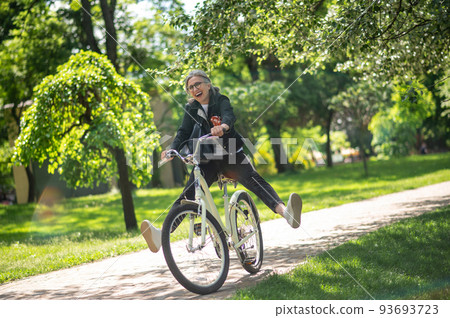 A woman in black clothes riding a bike and having fun A woman in black clothes riding a bike and having fun 93693723