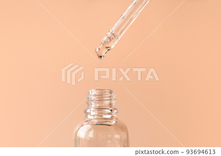 Pipette with transparent fluid hyaluronic acid or serum. Cosmetics, science and healthcare concept closeup. Dose of serum or retinol falls in a bottle. Front view. Beauty product presentation, macro Pipette with transparent fluid hyaluronic acid or serum. Cosmetics, science and healthcare concept closeup. Dose of serum or retinol falls in a bottle. Front view. Beauty product presentation, macro 93694613