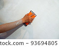 the builder grinds the wall from irregularities after applying putty 93694805