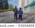 the older brother leads the younger brother by the hand around the city 93694808