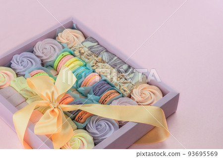 Macaroons and marshmallows in box in pink background, closeup. Traditional colored sweet desserts for present for the holiday. 93695569