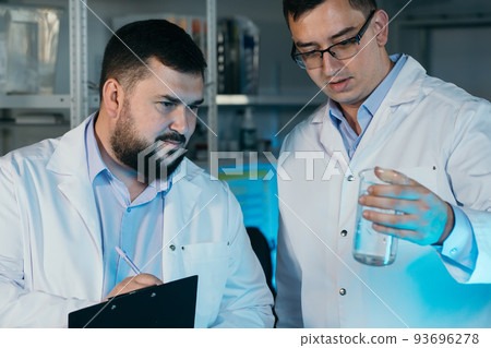 Young chemical technician checking liquid reagent in laboratory 93696278