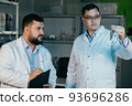 Young chemical technician checking liquid reagent in laboratory 93696286
