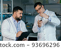 Male scientist with a large flask in his hands. He examines some liquid in a test tube. Working in a scientific laboratory. 93696296