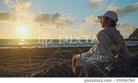 Man on a beach is looking distance during beautiful summer sunset. Human looks to the sun over horizon in the morning while sunrise. Happy person contemplates the beauty of nature. Freedom concept. Man on a beach is looking distance during beautiful summer sunset. Human looks to the sun over horizon in the morning while sunrise. Happy person contemplates the beauty of nature. Freedom concept. 93696768