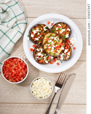 Homemade grilled eggplant with feta and tomatoes on a white table, top view. Homemade grilled eggplant with feta and tomatoes on a white table, top view. 93697947