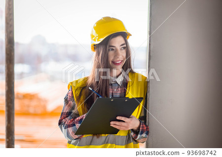 Woman inspects the buildings process at a construction site. 93698742