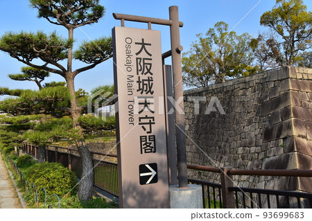 日本大阪府，春天的大阪城，壯麗的石牆和通往城堡塔的指南牌 93699683