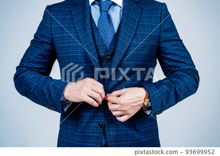 Buttoning up male vested blue suit with tie in formal fashion style grey background, formalwear Buttoning up male vested blue suit with tie in formal fashion style grey background, formalwear 93699952