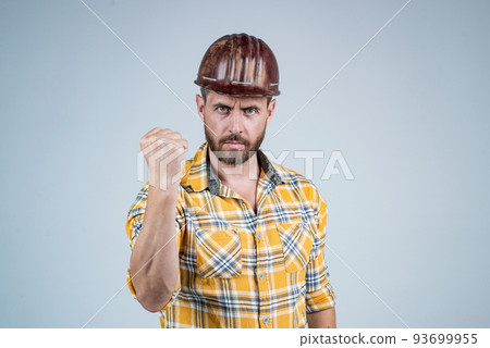 man builder in safety helmet and checkered shirt demonstarte power with fist, male strength. 93699955
