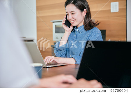A young woman calling on a smartphone during telework A young woman calling on a smartphone during telework 93700604