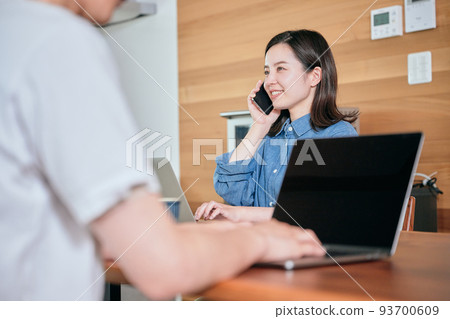 A young woman calling on a smartphone during telework A young woman calling on a smartphone during telework 93700609