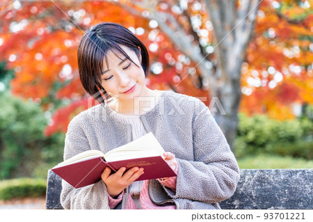 秋葉在公園長椅上閱讀的年輕女子 93701221