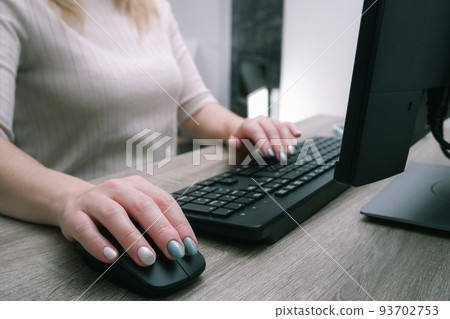 Businesswoman working on a computer from home during pandemic to prevent disease. Remote work. Selective focus. Hands, mouse, keyboard. Cropped shot of woman typing on keyboard and working with Businesswoman working on a computer from home during pandemic to prevent disease. Remote work. Selective focus. Hands, mouse, keyboard. Cropped shot of woman typing on keyboard and working with 93702753