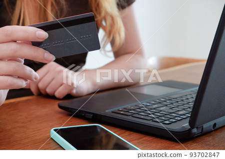 Woman with laptop and credit card at home . Online payment, digital banking. Online shopping concept, young woman hands holding mobile smart phone and credit card with laptop on table. Woman with laptop and credit card at home . Online payment, digital banking. Online shopping concept, young woman hands holding mobile smart phone and credit card with laptop on table. 93702847