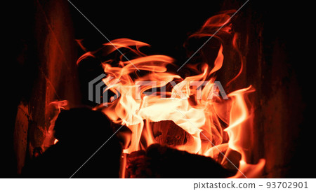Burning firewood and coals in a stone stove. Brick oven on wood. Long tongues of flame of burning fire 93702901