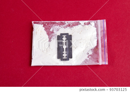 Razor and pack of cocaine powder for snorting isolated on red. Top view close-up. 93703125