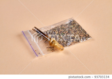 Glass pipette cigarette and pack of weed on beige background. Drug addicted smokers accesories. Glass pipette cigarette and pack of weed on beige background. Drug addicted smokers accesories. 93703134