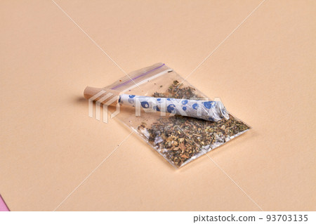 Close-up joint and packet of weed isolated on beige background. Marijuana smoking accessories. 93703135