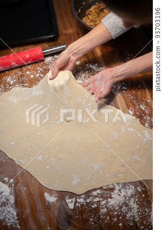 View from above of a woman pulling and stretching homemade pastry dough for strudel or pie View from above of a woman pulling and stretching homemade pastry dough for strudel or pie 93703196