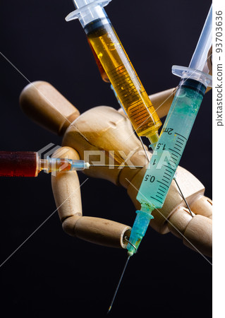 Close-up wooden doll dummy mannequin with stucked syringes. Drug trap concept. 93703636