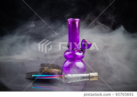 Purple glass bong pipe with joint and a lot of smoke. Cannabis smoker starter pack. Purple glass bong pipe with joint and a lot of smoke. Cannabis smoker starter pack. 93703691